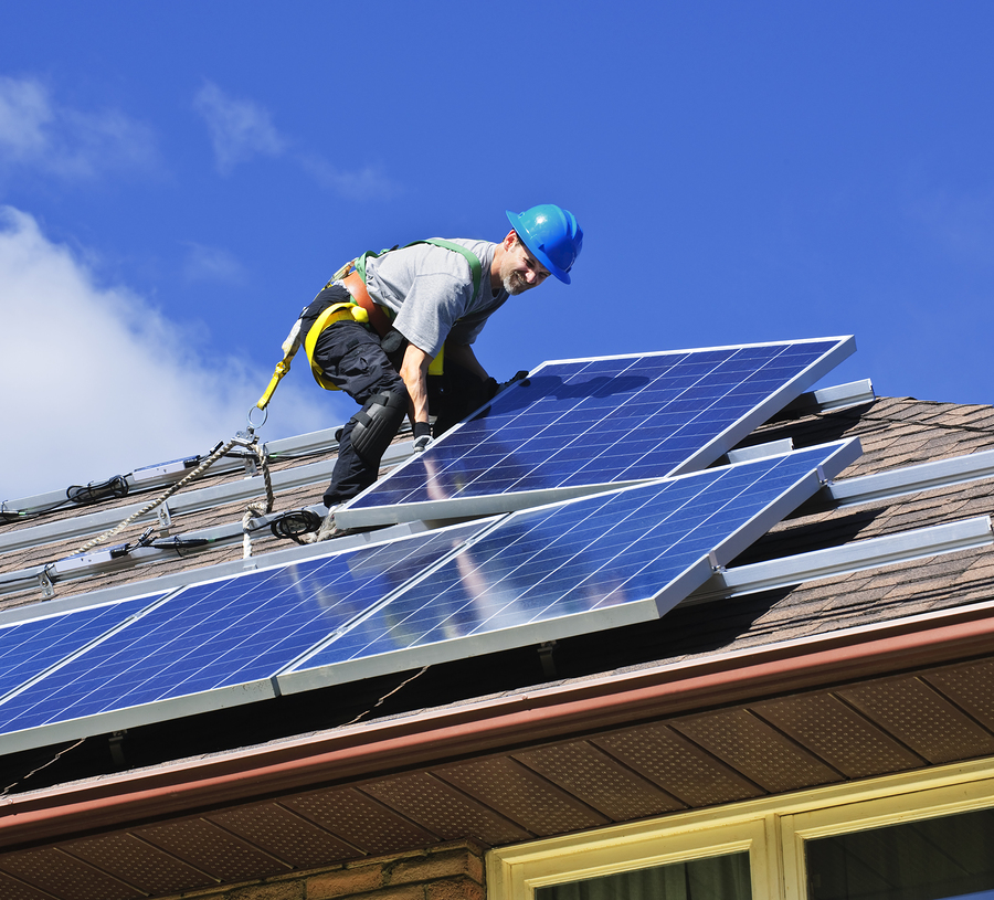 worker removing defective solar panels from a residential roof